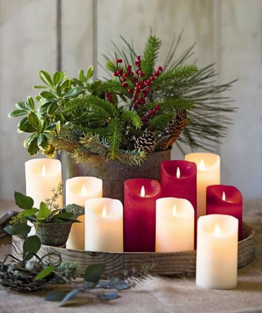 led candles in a tray surrounding a planter with holiday greens