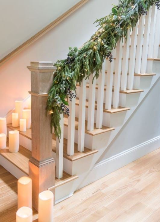 led candles on stairs and faux evergreens on staircase railing